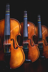 Fototapeta na wymiar Row of multiple violins hanging on the wall, musician workshop