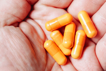 Medicine background. Orange pills isolated on white. Pile of capsules. Tablets background. Vibrant vivid color drugs. Antibiotics background. Holding orange pills. Drugs on hand. Diet supplementation.