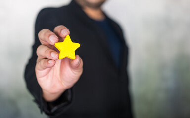 A man in a suit holding a yellow star. Perfect for recognizing achievements and success