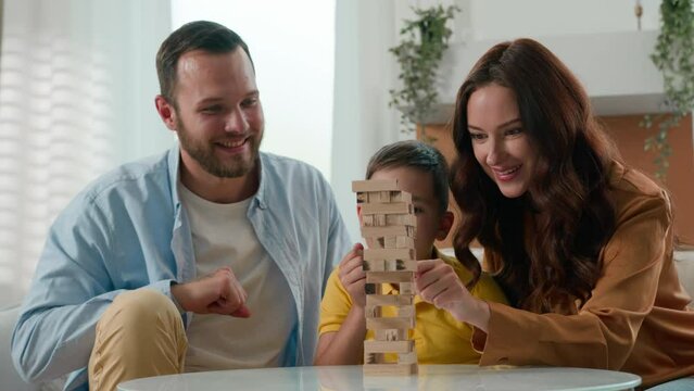 Happy loving playful Caucasian family mother father mom dad parents beloved son kid boy child play intellectual logical board game together in cozy living room playing tower puzzle enjoy games at home