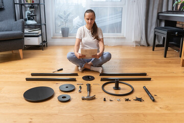 A woman with instructions in her hands studies the sequence of actions for self-assembly of...