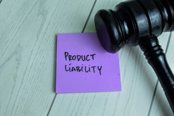 Concept of Product Liability write on sticky notes with gavel isolated on Wooden Table.