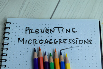 Concept of Preventing Microaggressions write on book isolated on Wooden Table.