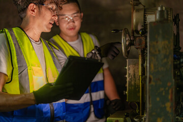 Asian workers in production plant drilling at machine. Professional worker near drilling machine on factory. finishing metal working internal steel surface on lathe grinder machine with flying sparks.