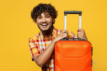 Traveler smiling Indian man wear shirt casual clothes hold suitcase isolated on plain yellow...