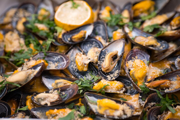 Close-up of baked mussels with parsley garnish in spicy sauce.  Fresh out of the oven.  Seafood concept.