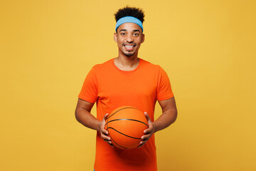 Young fitness trainer instructor sporty man sportsman wear orange t-shirt hold in hand basketball...