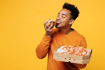 Young happy man he wears orange sweatshirt casual clothes holding italian pizza in cardboard...