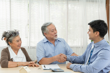 Happy smiling Asian retired senior couple making purchase and mature man handshake with real estate...