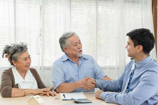 Happy smiling Asian retired senior couple making purchase and mature man handshake with real estate agent, Sales man closing deal from business agreement contract, Healthy living and insurance