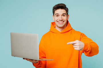 Young happy IT man he wears orange hoody casual clothes hold use work point finger on laptop pc...
