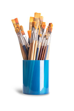 Paintbrushes in a blue plastic cup. Numerous used flat and round paintbrushes of various sizes, used by artists in one stroke painting. The bristles are made of natural and synthetic hairs. Photo.