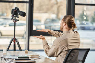 back view of entrepreneur gesturing in front of digital camera at work desk in modern office