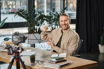happy businessman pointing at bitcoins and recording video blog on digital camera in office