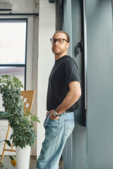 Fototapeta premium successful businessman in black t-shirt standing with hands in pockets and looking at camera