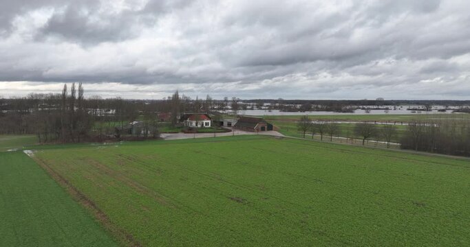 Rising aerial shot of river overflowing, flooding and farm houses at danger.