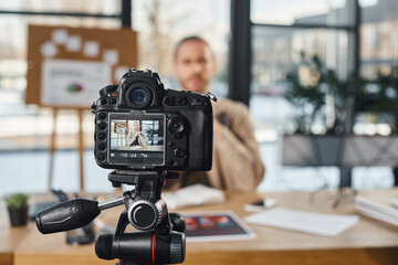 selective focus of professional digital camera near businessman recording video content in office - obrazy, fototapety, plakaty