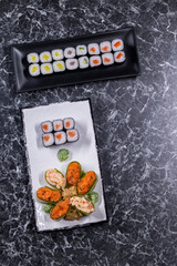 set of sushi rolls with seafood on a black stone background