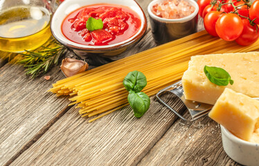 Ingredients for cooking pasta tomato sauce, cheese parmesan, tomatoes and basil on a wooden background. top view. copy space