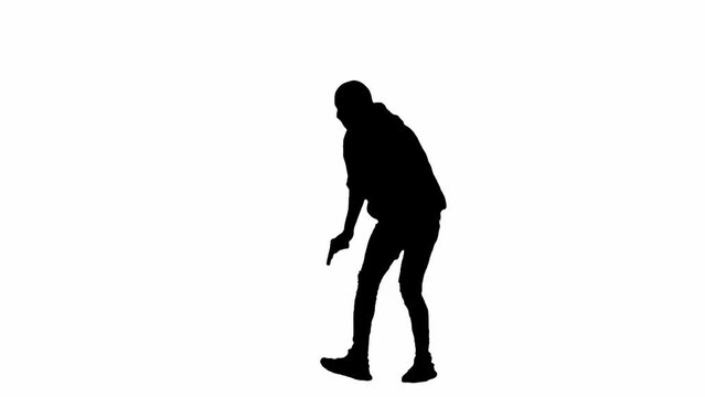 Black silhouette of thief on isolated white background. Male robber in hoodie and balaclava walking with a gun in his hands, preparing to commit a crime. Half-turn.