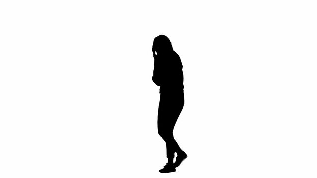 Black silhouette of a woman on a white isolated background. A young girl walks, looking around frightened, fleeing faster from danger. Half turn.
