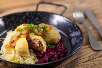 dumpllings filled with smoked meat served with red and white cabbage