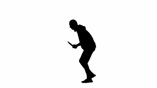 Black silhouette of thief on isolated white background. A male robber in a hoodie and balaclava walks with a knife in his hands, preparing to commit a crime. Side view.