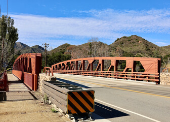 rust colored steel bridge across the creek