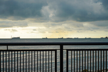 Rows of industrial cargo ships queuing on the ocean outside. International maritime freight stretching out to the horizon