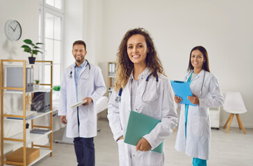 Dedicated team of doctors, nurses, and physicians, dressed in lab coats, stands together in the hospital. They radiate teamwork, showcasing the collaborative spirit of these healthcare professionals. - Powered by Adobe