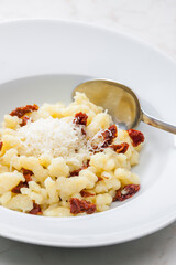 potato dumplings called halusky with dry tomatoes and grated cheese