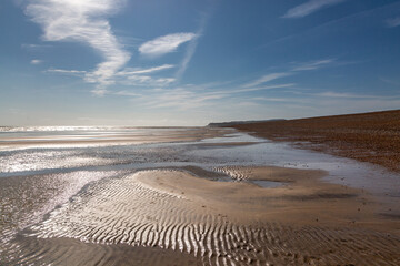 Looking along Winchelsea Beach in East Sussex on a sunny day, with the cliffs at Pett Level in the far distance