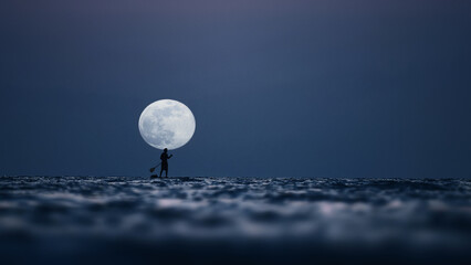 Silhouette of a man on the paddleboard against the rising moon. Paddleboard in the sea at night,...
