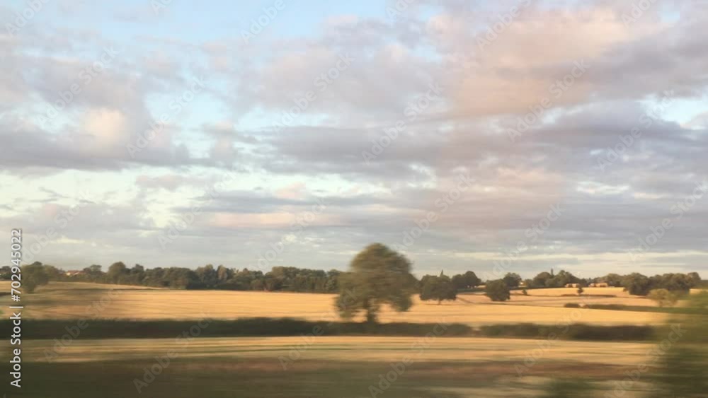 Wall mural wide shot view of landscape from train window of fields and trees going past typical fields south west England landscape 