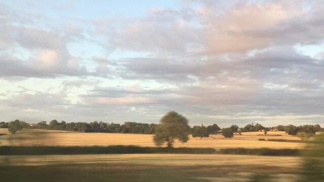 wide shot view of landscape from train window of fields and trees going past typical south west England landscape 