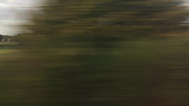 wide shot view of landscape from train window of fields and trees going past typical south west England landscape - video footage