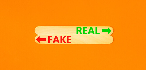 Real or fake symbol. Concept word Real or Fake on beautiful wooden stick. Beautiful orange table...