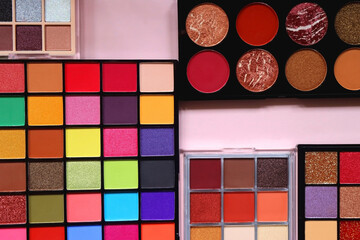 Various colorful eyeshadow palettes on bright pink background. Flat lay.