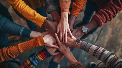 Fotobehang A top-down view of a group of friends stacking their hands together, symbolizing unity, teamwork, and mutual support in a casual setting. © MP Studio