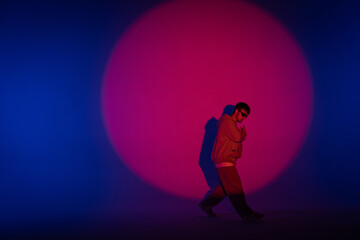 Guy in casual clothes dancing hip hop elements in studio with blue light. Dancer is in red circle...