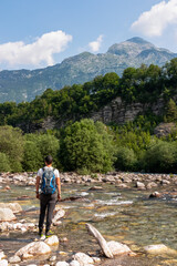Hiker man with backpack with scenic view of Soca River, Bovec, Triglav National Park,Slovenia. Magnificent Soca Valley in Julian Alps. Wanderlust in untamed Slovenian Alps. Hiking in alpine wilderness - obrazy, fototapety, plakaty