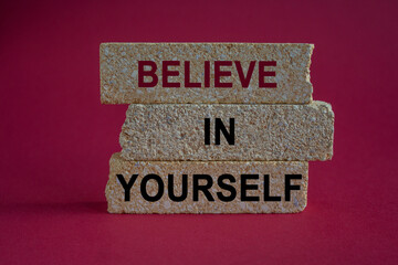 Believe In Yourself symbol. Phrase Believe In Yourself on brick blocks. Beautiful red background. Motivational quote