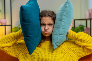 Repair work at neighbors. Irritated child girl kid puffed out her cheeks cover ears with pillows...