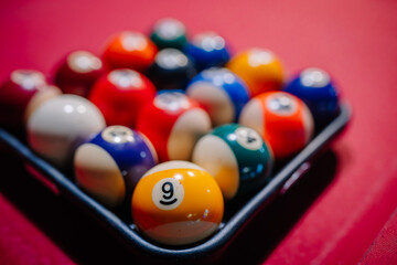 Close-up of a triangle rack of billiard balls on a red felt pool table, focus on the yellow number 9 ball
