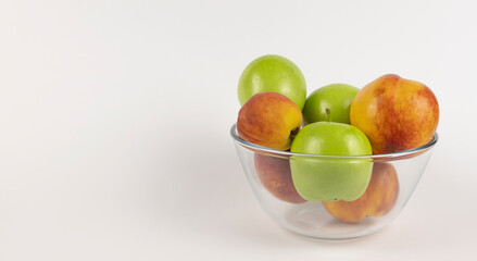 Green apples and orange nectarine in a glass bowl on the table. Granny Smith apples.