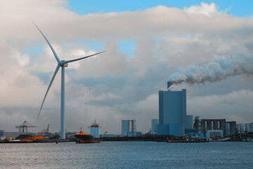 Container Ship In The Port With The Largest Wind Generator In The World And Coal Power Station In The Background