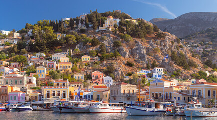 Fototapeta na wymiar Multi-colored facades of houses in the village of Symi at sunset.
