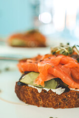 Healthy breakfast. Avocado toasts with salmon and poached eggs on ceramic plate