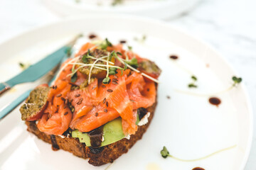 Healthy breakfast. Avocado toasts with salmon and poached eggs on ceramic plate