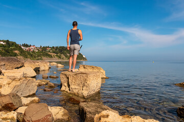 Tourist man standing on rock with scenic view of idyllic coastline of Gulf of Piran, Adriatic...